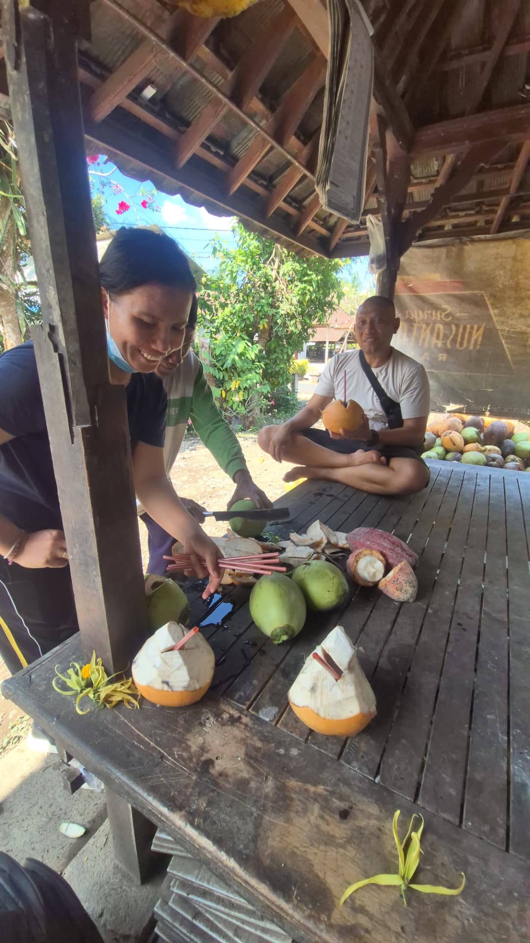 Verse kokosnoten worden geopend en van rietjes voorzien in een houten warung op Bali