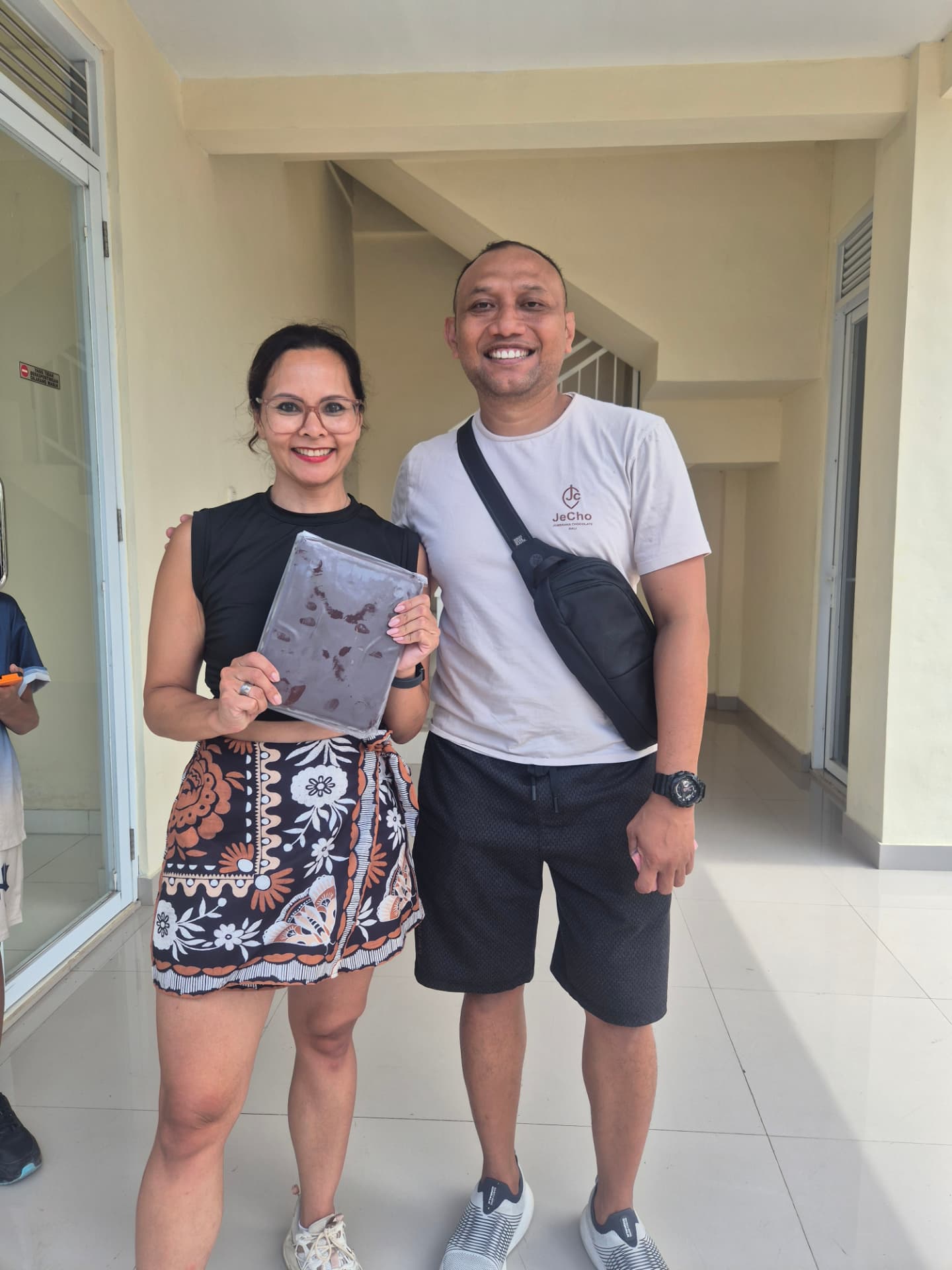 Cenny met een grote plak pure Balinese cacaopasta, samen met de cacaomaker bij de fabriek